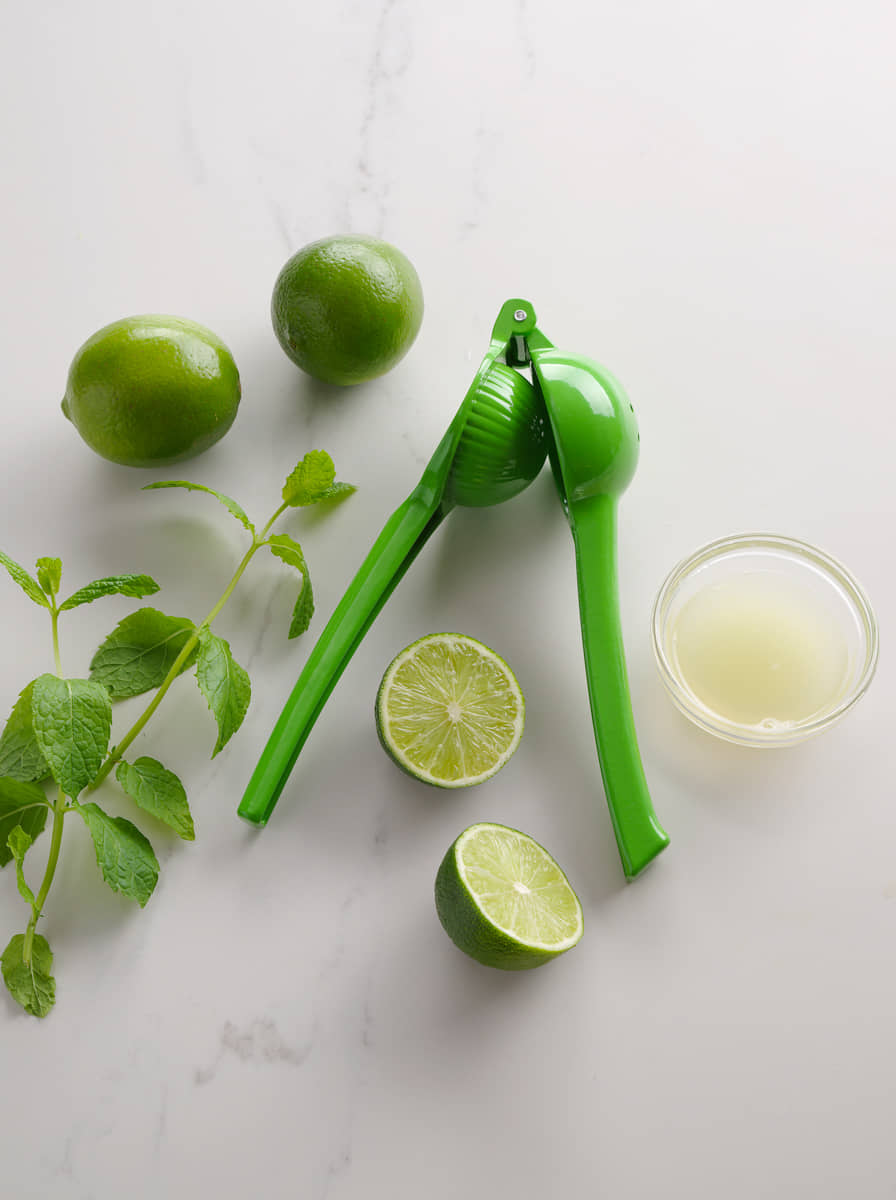 Grüne Zitruspresse mit Limetten und Limettensaft