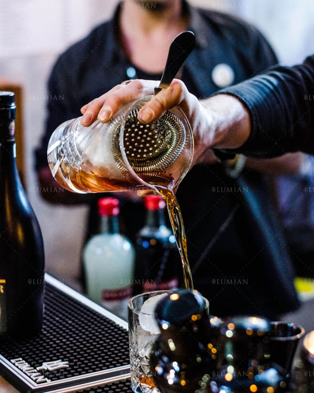 Cocktail mit goldenem Barsieb eingießen