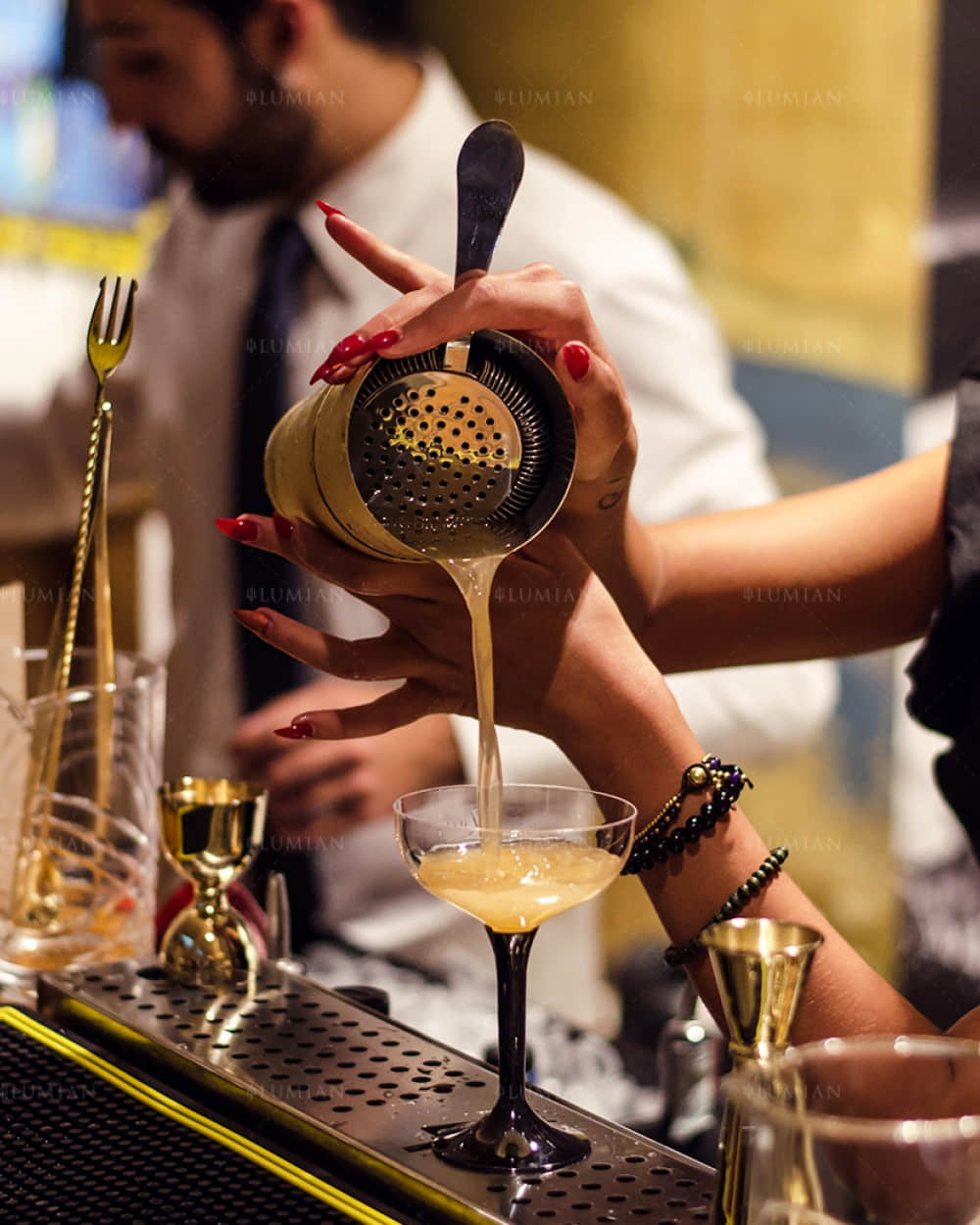 Cocktailshaker gießt Cocktail in Glas