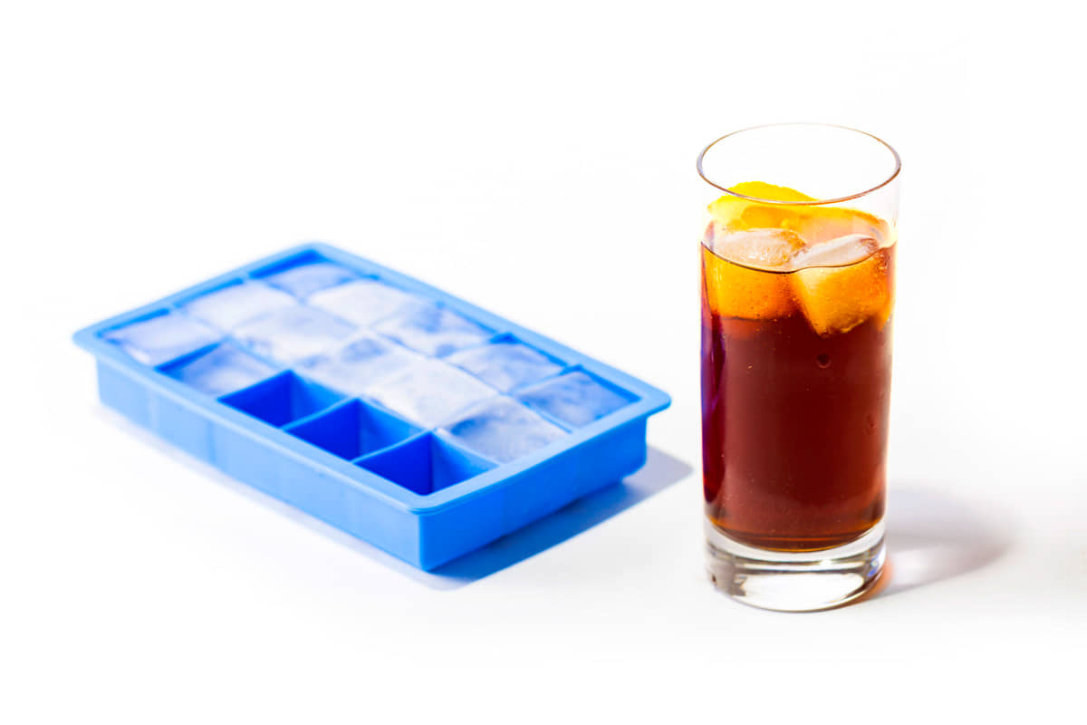 Eiswürfelform mit Rum-Cola Drink daneben