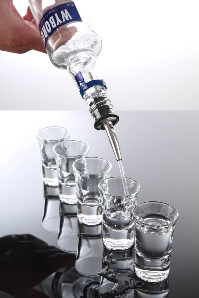 Schnapsgläser werden mit Vodkaflasche und Ausgießer befüllt