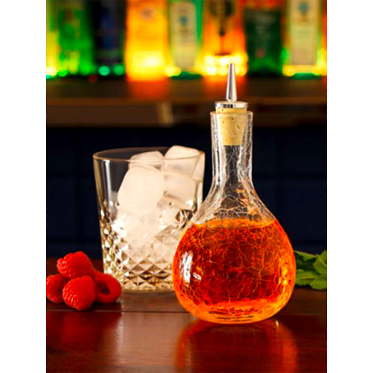 Bitterflasche Craquele mit rotem Cocktail-Bitter gefüllt vor Tumbler mit Eiswürfeln