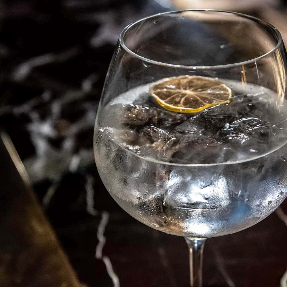 Gin Tonic Ballonglas mit Eis und Zitronenscheiben gefüllt