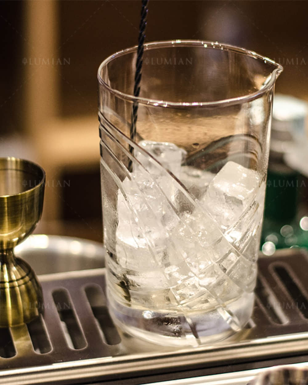 Barmaß in Bronze neben Cocktail Rührglas mit Eis
