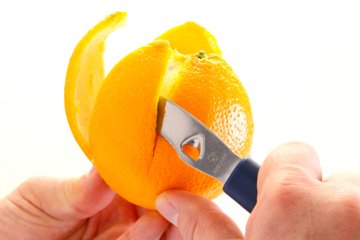Zitrusschäler schält eine Orangen
