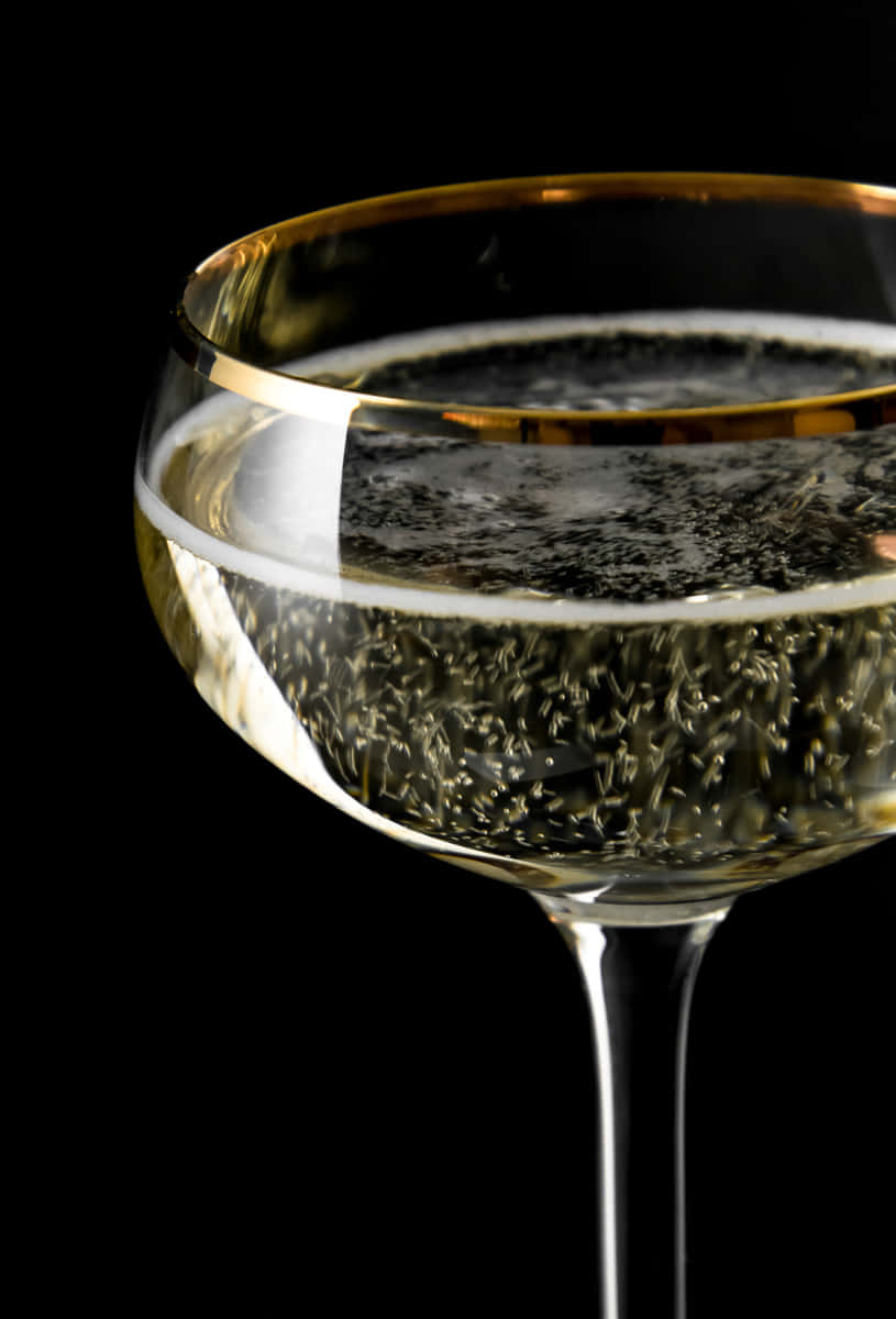 Retro Coupe Cocktailglas mit Goldrand und Champagner gefüllt